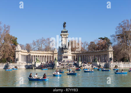 Tourists rowing traditional blue boats on lake in Retiro city park on a nice sunny winter day in Madrid, Spain. Stock Photo