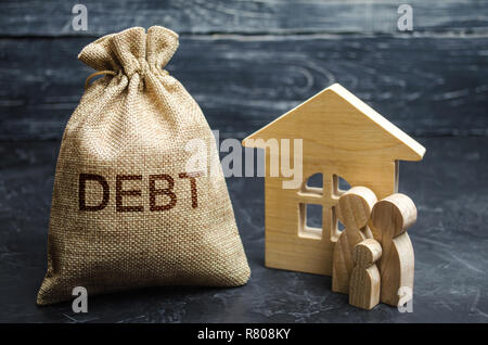 A bag of money with the word Debt and the family standing near the house. The concept of debt for housing. Mortgage. Real estate, home savings, loans  Stock Photo