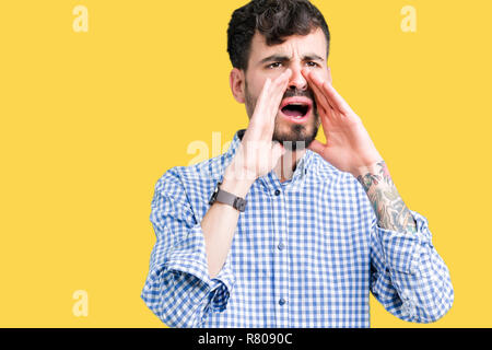 Young handsome business man over isolated background Shouting angry out loud with hands over mouth Stock Photo