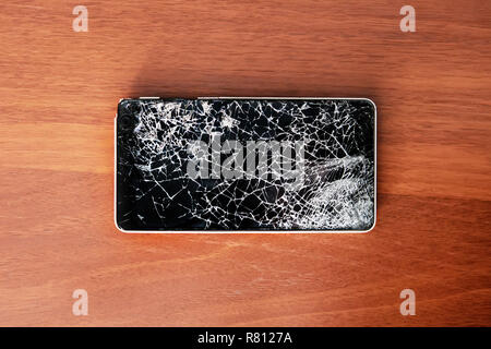 Smartphone with broken screen on the wooden table Stock Photo
