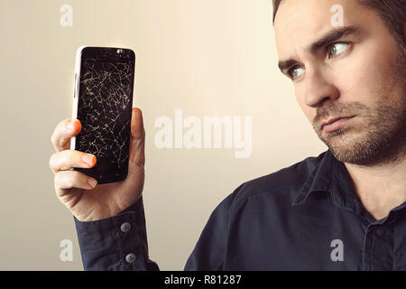 Young businessman with broken smartphone. Stock Photo
