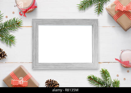 Horizontal photo frame surrounded with Christmas New Year gifts, tree branches and decorations. Isolated frame for photo mockup. Stock Photo