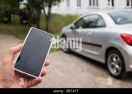 Mobile phone apps for car owners concept. Man using smart phone to check status, control his new car. Blank Empty mobile phone screen for design. Stock Photo