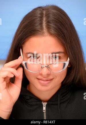 Young dark-haired woman looking over her eye glasses, portrait, Sweden Stock Photo