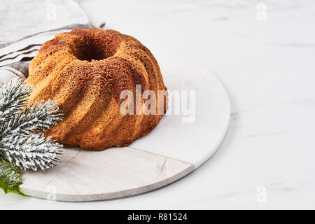 Vanilla and chocolate marble bundt cake on marble serving plate over white marble table with copy space for text. Stock Photo