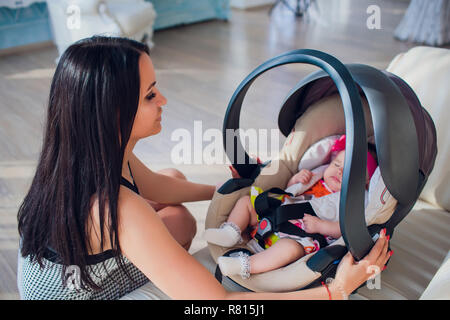 family transportation security car trip and people concept happy mother fixing baby girl in baby seat at home Stock Photo Alamy