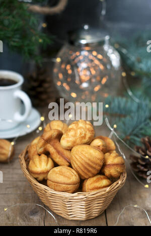 Homemade shortbread cookies in various shapes, filled with caramel on the background of fir branches and garlands. Stock Photo