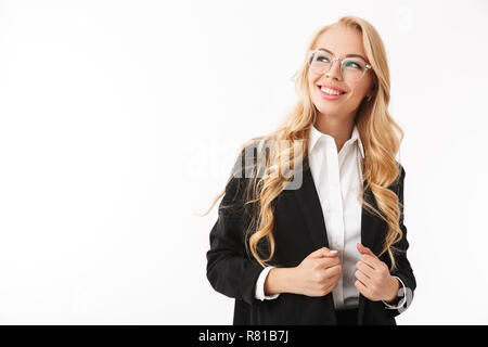 Photo of charming businesswoman wearing office suit and eyeglasses smiling while looking aside isolated over white background in studio Stock Photo