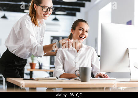 Photo of a happy cheerful colleagues business women in office working while using computer. Stock Photo