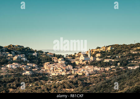 The ancient mountain village of Corbara lit by the afternoon sun and surrounded by autumnal trees in the Balagne region of Corsica with the Mediterran Stock Photo