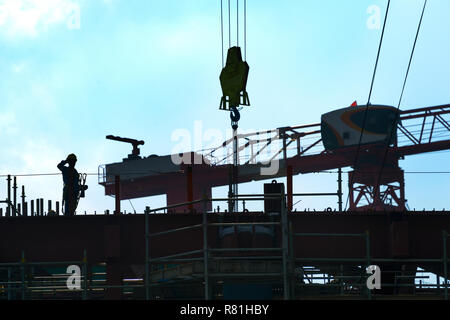 Silhouette of construction worker at construction site. Cranes Stock Photo