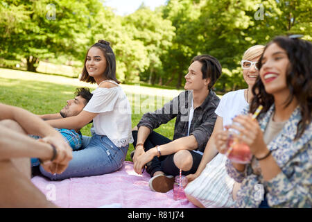 happy friends with drinks at picnic in summer park Stock Photo