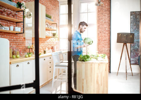Man cooking healthy food standing on the kitchen of the beautiful loft apartment