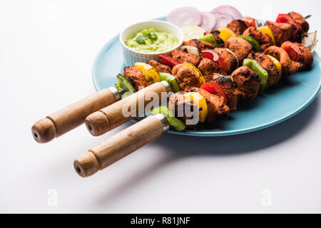 Chicken tikka /skew Kebab. Traditional Indian dish cooked on charcoal and flame, seasoned & colourfully garnished. served with green chutney and salad Stock Photo