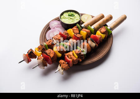 Chicken tikka /skew Kebab. Traditional Indian dish cooked on charcoal and flame, seasoned & colourfully garnished. served with green chutney and salad Stock Photo