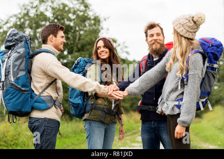friends with backpacks hiking and stacking hands Stock Photo