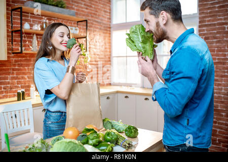 Young couple of vegetarians enjoying fresh green food stading on the kitchen at home Stock Photo