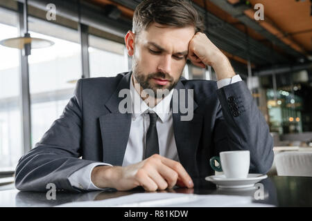 Businessperson on business lunch at restaurant sitting drinking espresso looking down thinking Stock Photo