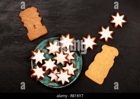 A photo of an assortment of traditional Christmas Spekulatius and Zimtsterne cookes, shot from above on a dark background with copy space Stock Photo