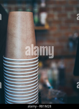 Stack of small brown paper cups made of craft paper prepared for coffee, tea or water in loft style  cafe background with copy space. Stock Photo