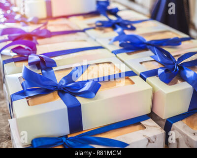 White souvenir gift boxes with blue ribbons for guest attending the wedding. Stock Photo