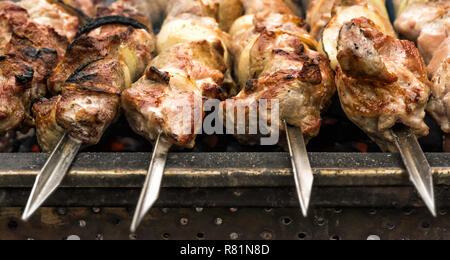 Just roasted hot pieces of meat and onion on few metal skewers on metal brazier full of hot charcoal.  This barbecue and picnic dish called shashlik i Stock Photo