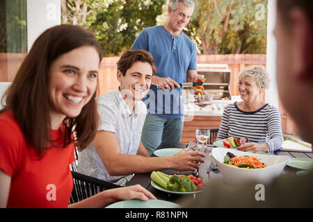 Senior dad serving his family food at barbecue in the garden Stock Photo