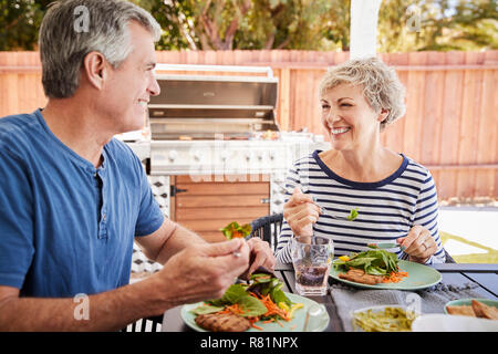 Senior white couple eating together at a table in the garden Stock Photo