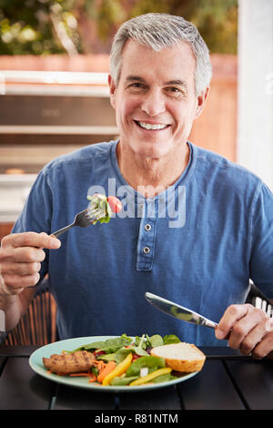 Senior white man eating lunch at a table outside, vertical Stock Photo