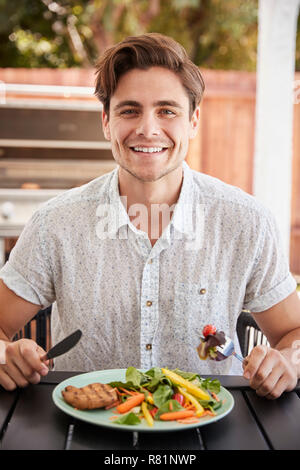 Young white man eating lunch at a table in the garden Stock Photo