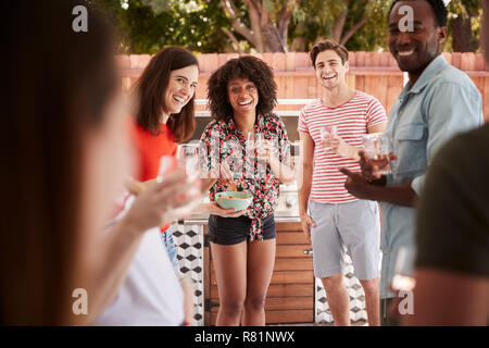 Young adult friends standing with drinks at a backyard party Stock Photo