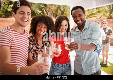 Adult friends at a backyard party raising glasses to camera Stock Photo