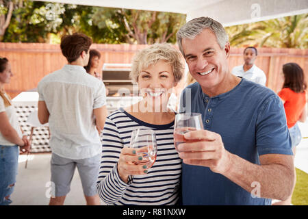 Senior couple at a backyard party raising glasses to camera Stock Photo