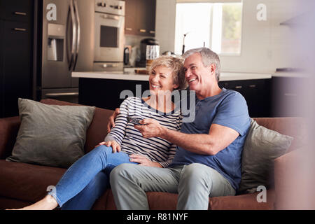 Senior white couple relaxing on couch watching television Stock Photo