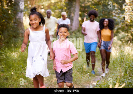 Two kids ahead of their family during a walk in a forest Stock Photo