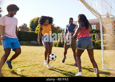 Two black adult couples playing football in garden Stock Photo