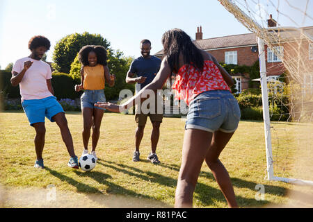Black adult friends having a fun game of football in garden Stock Photo