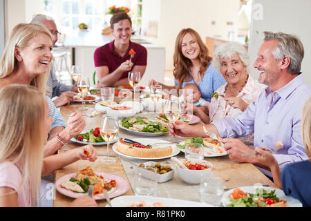 Group Of Multi-Generation Family And Friends Sitting Around Table And Making A Toast Stock Photo