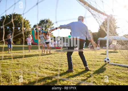 Children Playing Football Match With Senior Man At Summer Garden Fete Stock Photo