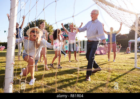 Children Playing Football Match With Adults At Summer Garden Fete Stock Photo