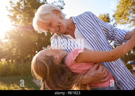 Grandmother Playing Game And Dancing With Granddaughter In Summer Park Stock Photo