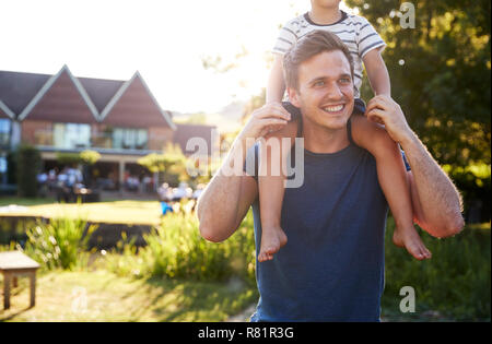 Father Giving Son Ride On Shoulders In Garden Of Pub Stock Photo