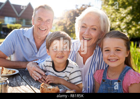 Portrait Of Grandparents With Grandchildren Enjoying Outdoor Summer Snack At Cafe Stock Photo