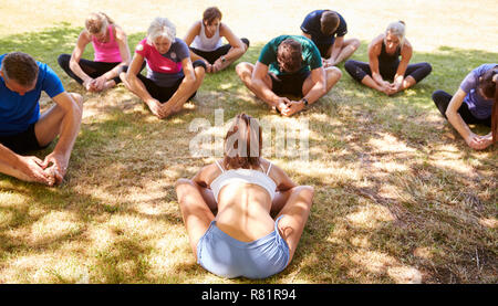Female Instructor Leading Outdoor Yoga Class Stock Photo