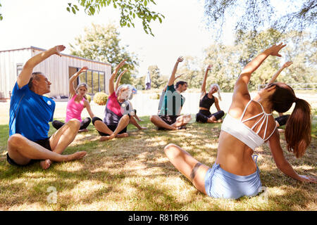 Female Instructor Leading Outdoor Yoga Class Stock Photo