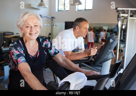 Portrait Of Active Senior Woman Resting After Exercising On Cycling Machines In Gym Stock Photo