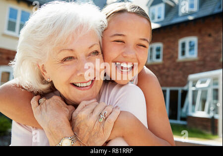 Granddaughter Hugging Grandmother On Bench During Visit To Retirement Home Stock Photo