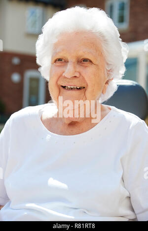 Portrait Of Senior Woman Sitting Outside Retirement Home Stock Photo