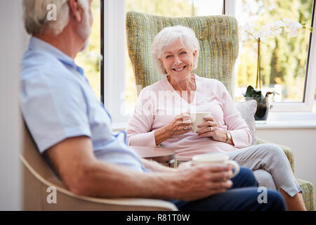 Senior Couple Sitting In Chairs And Chatting In Retirement Home Stock Photo