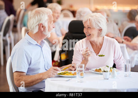 Senior Couple Eating Meal And Talking In Retirement Home Stock Photo
